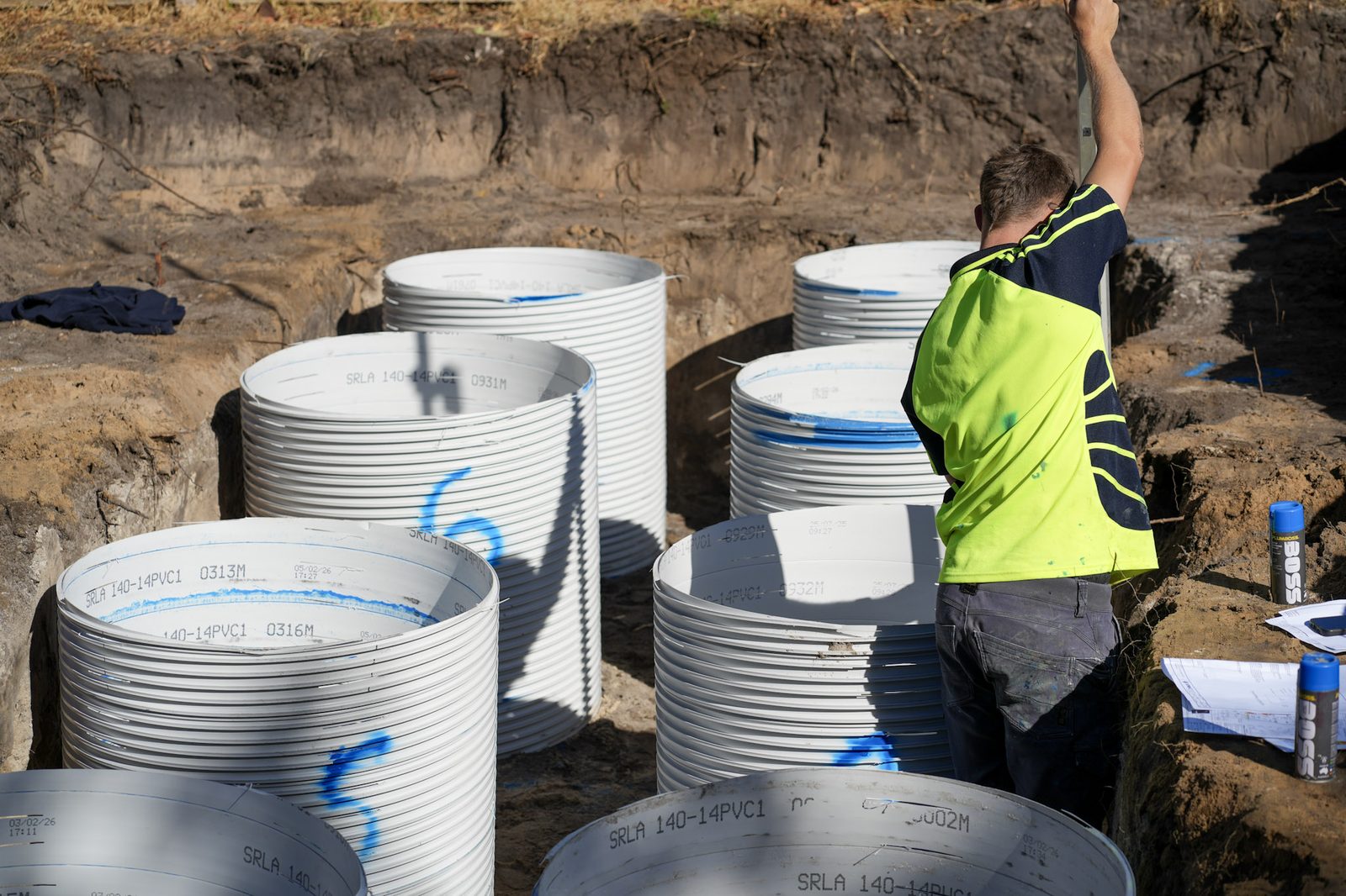Crew installing precast concrete drainage pits in an excavated trench.