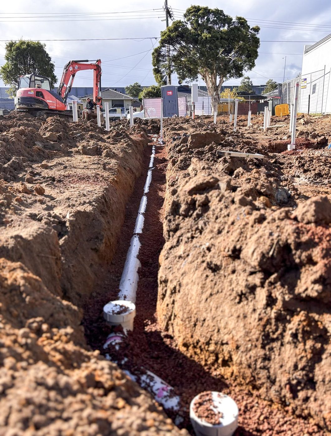 Deep drainage trench with pipe laid and graded before backfill.