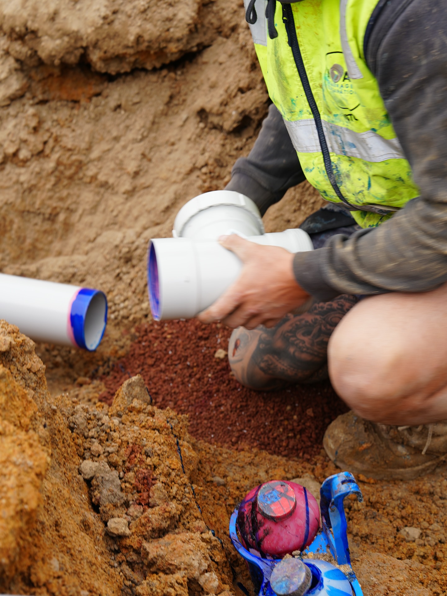 Worker fitting a DWV junction by hand in the trench.