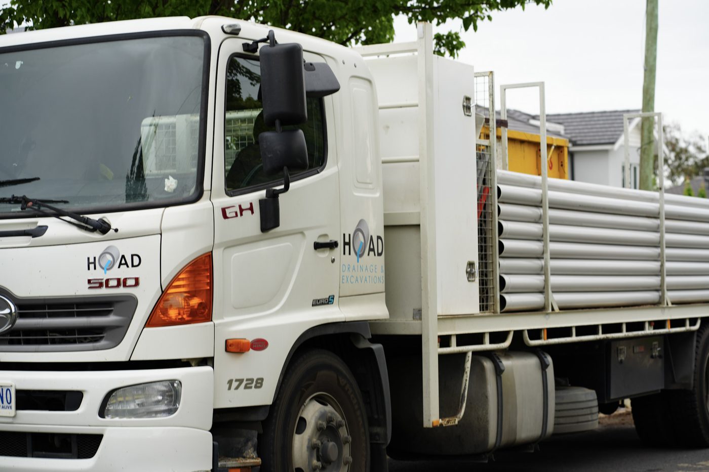 Branded Hoad Drainage Hino 500 tray truck loaded with PVC pipe.