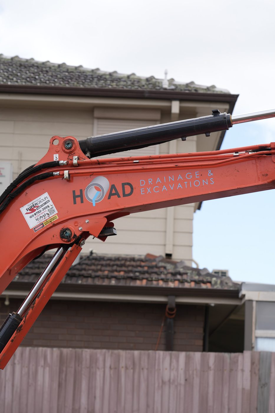 Excavator digging close in beside a house.